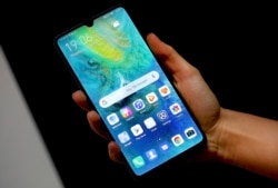 FILE - A staff member holds a Huawei 'Mate20 X 5G' smartphone at the IFA 2019 tech fair in Berlin, Germany, Sept. 5, 2019.