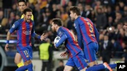 Lionel Messi de Barcelone, au centre, court, balle en main, en compagnie de ses co-équipiers Neymar, à gauche, et Gerard Piqué, après son but sur penalty lors d’un match de la Ligue des champions entre le FC Barcelone et Paris Saint Germain au stade Camp 
