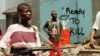 FILE - Street fighters with ULIMO-J walk past graffiti in the Liberian capital of Monrovia in this May 1996 photo.