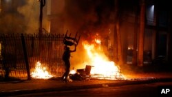 A protester carries a chair to a fire outside the Congress building during clashes between police and protesters opposing a constitutional amendment that would allow the election of a president to a second term, in Asuncion, Paraguay, March 31, 2017.