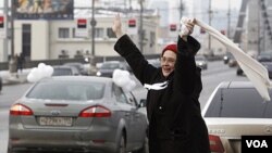 Seorang pendukung oposisi menyambut iring-irigan mobil anti-Putin berhias balon putih di Moskow (19/2).