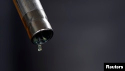 A drop of diesel is seen at the tip of a nozzle after a fuel station customer fills her car's tank in Sint Pieters Leeuw, Dec. 5, 2014. 