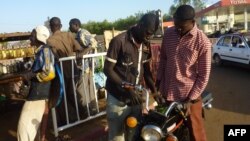 Un homme achète de l'essence au marché noir pour sa moto dans le quartier Lazaret de Niamey, le 5 janvier 2012. 