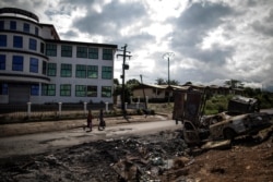FILE - An abandoned market in Cameroon's majority anglophone Southwest province in Buea, is seen Oct. 3, 2018, next the wreckage of a car allegedly burned by separatists fighters.