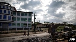 FILE - An abandoned market in Cameroon's majority anglophone South West province in Buea, is seen Oct. 3, 2018, next the wreckage of a car allegedly burned by separatists fighters.