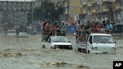 FILE - Pakistani commuters travel on a flooded street following a heavy rainfall in Karachi, Pakistan, Aug. 31, 2017.