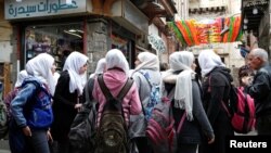 រូបឯកសារ៖ ក្មេងស្រីសិស្សសាលាមួយក្រុមឈរខាងក្រៅហាងមួយនៅក្រុង Damascus ប្រទេសស៊ីរី កាលពីថ្ងៃទី១២ ខែមីនា ឆ្នាំ២០២០។