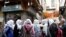 FILE - A group of school girls stand outside shops in the old city of Damascus, Syria, March 12, 2020.