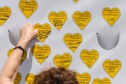 COVID-19 survivors gather at City Hall Park and place stickers representing lost relatives on a wall Aug. 7, 2021, in New York, as part of the largest nationwide day of awareness and action for COVID-19 survivors.