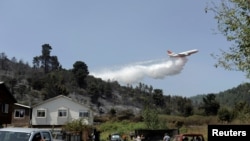 FILE - A DC-10 Air Tanker firefighting plane drops water to prevent a wildfire from spreading to homes near Concepcion, Chile, Feb. 12, 2019. 
