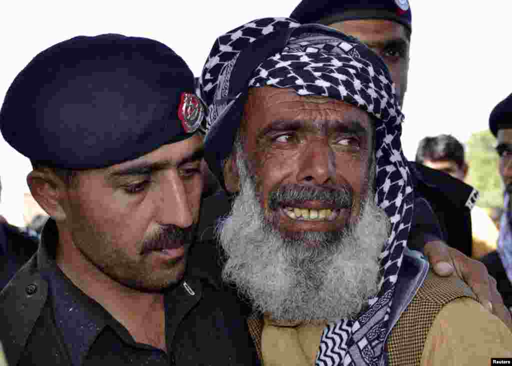 A police officer comforts a man whose son was killed in a bomb blast in Quetta, Pakistan, May 23, 2013.