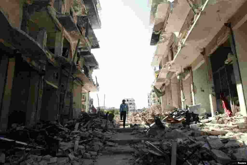 Mohammed al-Karaz, a Free Syrian Army fighter who said he lost one of his legs during the recent violence, uses his crutches to walk through a damaged street in the al-Soukhour neighborhood of Aleppo, Oct 5, 2013. 
