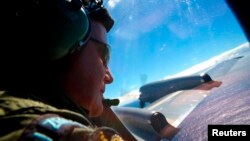 FILE - Sergeant Trent Wyatt looks out an observation window aboard a Royal New Zealand Air Force (RNZAF) P3 Orion maritime search aircraft as it flies over the southern Indian Ocean looking for debris from missing Malaysian Airlines flight MH370.