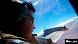 Seargent Trent Wyatt looks out an observation window aboard a Royal New Zealand Air Force (RNZAF) P3 Orion maritime search aircraft as it flies over the southern Indian Ocean looking for debris from missing Malaysian Airlines flight MH370.