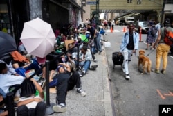 뉴욕시에 들어온 이주민들이 임시 거처로 사용되는 호텔 앞에 자리를 잡고 앉아있는 모습 (자료 사진)