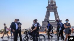 Police officers talk to a man while wearing protective face masks as precaution against the conoravirus at Tocadero plaza near Eiffel Tower in Paris, Sept. 14, 2020.