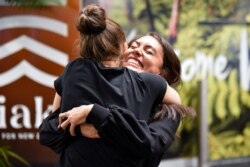 Families and loved ones embrace after arriving on the first Air New Zealand flight to land as quarantine-free travel between Australia and New Zealand begins, in Wellington, April 19, 2021.