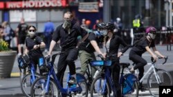 Cyclists wearing protective masks ride through Times Square, Saturday, April 25, 2020, in New York. New York is starting to test healthcare workers for coronavirus antibodies and will do the same next week with transit and law enforcement workers as…