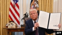 Donald Trump brandit un décret dans le bureau ovale de la Maison Blanche à Washington, DC, le 23 janvier 2025.