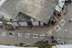 FILE - People keep their bags inside marked areas on a street as they wait to receive free rice distributed at a government store during a nationwide lockdown to prevent the spread of the coronavirus, in Hyderabad, India.