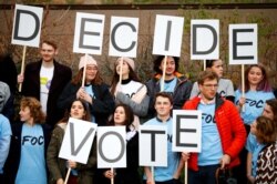 FILE - A group of young people hold up placards during a demonstration to demand a second referendum on Brexit outside the Houses of Parliament in London, Dec. 12, 2018.