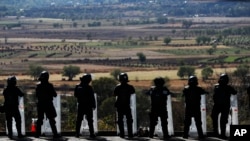 State police stand guard along the road leading into Uruapan, Michoacan state, Mexico, Feb. 6, 2020. In Uruapan, cartels are battling for territory and reports of killings are common.