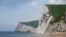 FILE - A man takes photographs pointing south on the beach at Durdle Door with the English Channel sea connecting Britain to mainland Europe seen behind, in south west England, May 13, 2016. 