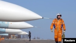 Seorang pilot berjalan melewati jet tempur SU-27SM di pangkalan udara militer di kota timur jauh Rusia, Vladivostok. Rusia mengerahkan dua pesawat bomber jarak jauh berkapasitas nuklir untuk berpatroli di atas wilayah Belarus barat. (Foto: Reuters)