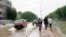 Les piétons marchent sur un trottoir boueux tandis que les véhicules pataugent dans une rue inondée par des pluies diluviennes à N'Djamena, au Tchad, le 19 août 2020. (Photo: André Kodmadjingar/VOA)
