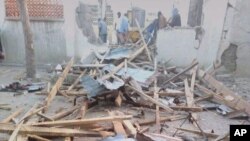 FILE - People stand near the damage following an attack on a mosque in the town of Gamboru in Borno state, Nigeria, Jan. 3, 2018.