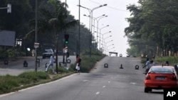 People walk on a road blocked by armed forces near the Ivorian state television station in the Cocody district of Abidjan, 18 Dec 2010