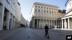 在意大利米兰，一名戴着口罩的男子正在骑着滑板车。（2020年3月11日）