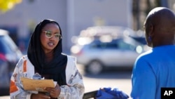 Mana Abdi, a Democratic candidate for state legislature, speaks with a resident while campaigning Thursday, Oct. 6, 2022, in Lewiston, Maine. 