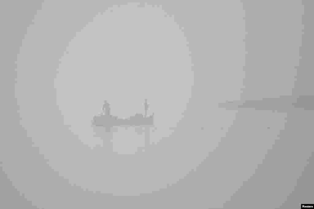 Рибари во едрилица рибаат среде смог рано наутро покрај реката Ченаб во Мултан, Пакистан.