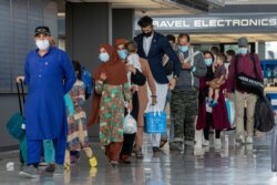 FILE - In this Aug. 31, 2021, file photo, families evacuated from Kabul, walk through the terminal to board a bus after they arrived in Washington.