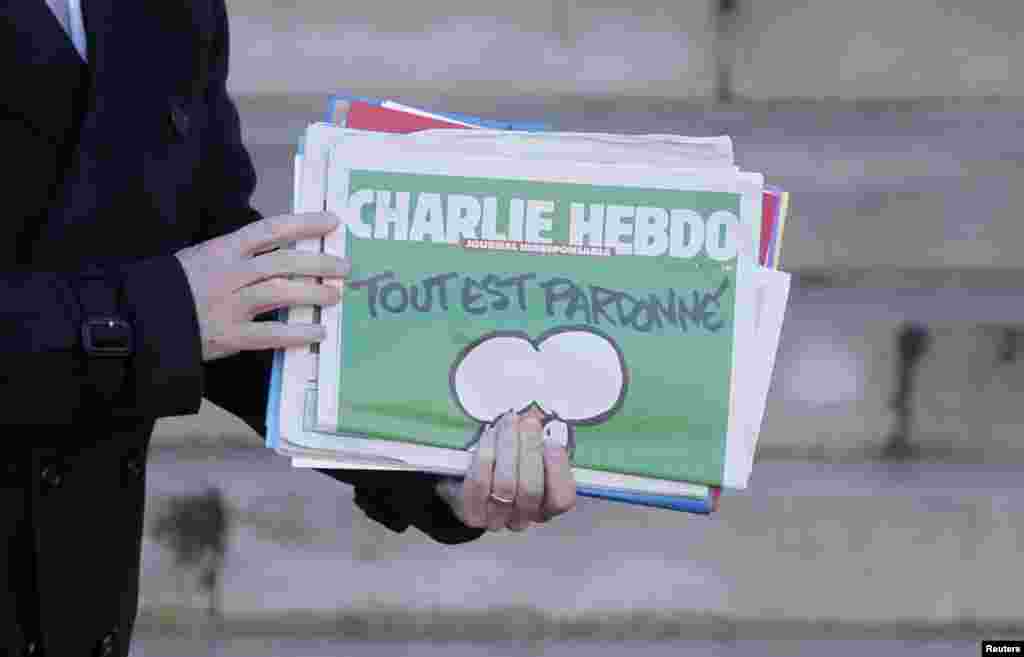 Perdana Menteri Perancis Manuel Valls memegang tabloid Charlie Hebdo saat ia meninggalkan rapat kabinet di Istana Elysee di Paris, Perancis (14/1). ​​(Reuters/Christian Hartmann)