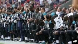Beberapa atlet Jaguars saling bergandengan tangan ketika lagu kebangsaan dinyanyikan, sebagian berlutut dan sebagian lainnya berdiri dalam pertandingan NFL di London, Inggris (24/9). 