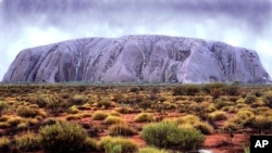 Ayers Rock (Uluru) takes on an unusual color as waterfalls cascade down its' walls in central Australia, Tuesday February 22, 2000 following the worst floods in the area for two decades. The rock which is usually a reddish colour is seldom seen like this.