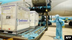 បុគ្គលិកសុខាភិបាលម្នាក់កំពុងបាញ់ថ្នាំសម្លាប់មេរោគលើប្រអប់ស្តុកទុកវ៉ាក់សាំងបង្ការជំងឺកូវីដ១៩ របស់ក្រុមហ៊ុនឱសថ AstraZeneca នៅអាកាសយានដ្ឋាន Tan Son Nhat ក្នុងទីក្រុងហូជីមិញ ប្រទេសវៀតណាម កាលពីថ្ងៃទី ២៤ ខែកុម្ភៈ ឆ្នាំ២០២១។