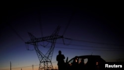 FILE - A man stands in front of power lines connecting pylons of high-tension electricity near Brasilia, Brazil, Aug. 29, 2018. 