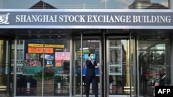 FILE - A woman leaves the Shanghai Stock Exchange building in Shanghai on Nov. 4, 2020. 