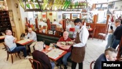 An employee, wearing a protective face mask, serves customers during the reopening of the hall of the Mesturet restaurant amid the coronavirus disease (COVID-19) in Paris, June 15, 2020. 