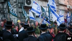 Anggota kelompok protes reservis 'Brothers in Arms' mengibarkan bendera Israel selama demonstrasi di lingkungan ultra-Ortodoks Mea Shearim, menuntut kesetaraan wajib militer, di Yerusalem, 31 Maret 2024. (Foto: AP)