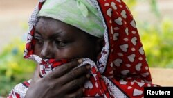 A woman reacts as members of the Kenya Defense Forces search for the bodies of missing people after flash floods wiped out several homes following heavy rains in Kamuchiri village of Mai Mahiu, Kenya, on May 1, 2024.