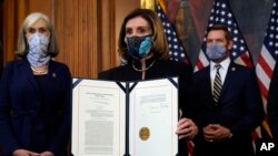 House Speaker Nancy Pelosi of Calif., displays the signed article of impeachment against President Donald Trump in an engrossment ceremony before transmission to the Senate for trial on Capitol Hill, in Washington, Wednesday, Jan. 13, 2021.