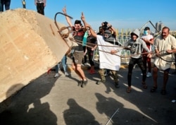 Anti-government protesters pull down concrete walls leading to the heavily guarded Green Zone during a demonstration in central Baghdad, Iraq, Oct. 25, 2019.