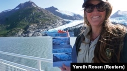 Chugach National Forest ranger Megan Parsley holds photos showing this summer's ice loss at the face of Portage Glacier, Alaska, U.S. August 17, 2019. 