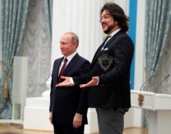 FILE - Pop singer Philipp Kirkorov reacts next to Russia's President Vladimir Putin after having been decorated with the Order of Honor during an awarding ceremony at the Kremlin in Moscow, Nov. 15, 2017.