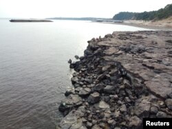 FILE - People are seen in the area where ancient stone carvings on a rocky point of the Amazon River were exposed after water levels dropped to record lows during a drought in Manaus, Amazonas state, Brazil October 23, 2023. (REUTERS/Suamy Beydoun)