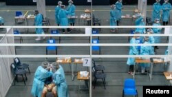 Medical professionals collect samples from a man at the community testing centre for the coronavirus disease (COVID-19) in Hong Kong, China September 1, 2020. (Anthony Kwan/Pool via REUTERS)